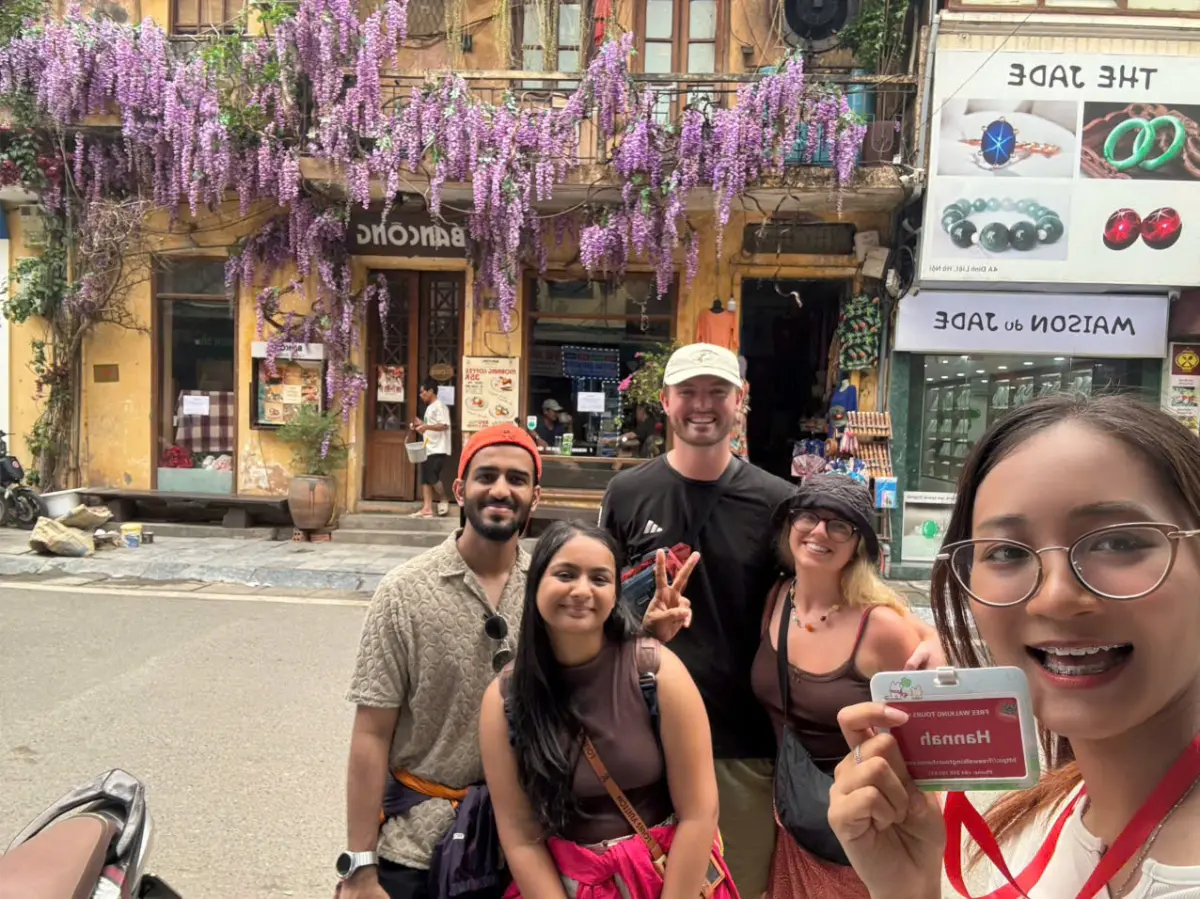 Travellers in front of a yellow colonial Old Quarter house draped in purple wisteria off Dinh Liet.